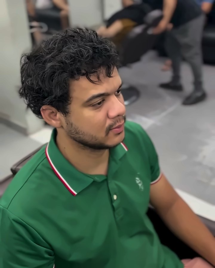 Cliente de camisa polo verde com o cabelo cacheado e volumoso, antes