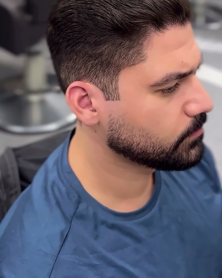 O mesmo cliente com o cabelo curto e alinhado e a barba desenhada, depois