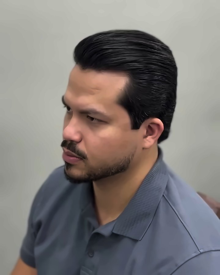 Cliente de camisa polo cinza com o cabelo liso e penteado para trás depois do corte com desondulação